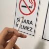 sigara yasaktır levhası önünde sigara içmek / #1555398